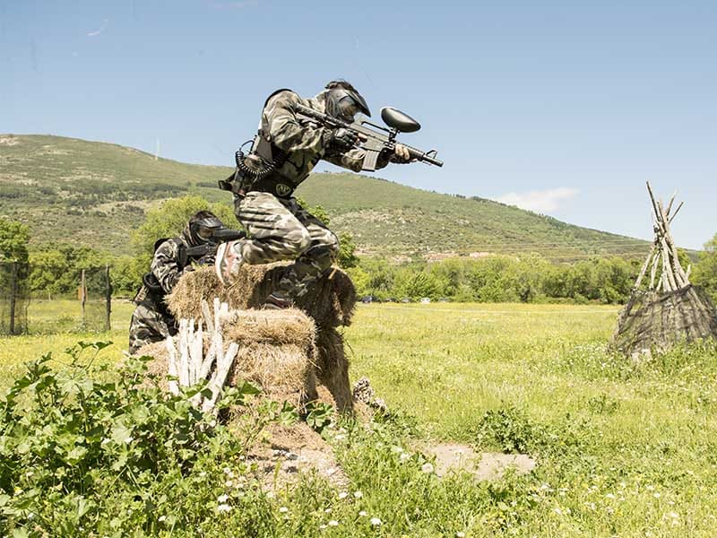 Jugador de paintball saltando por encima de un obstáculo en uno de nuestros campos