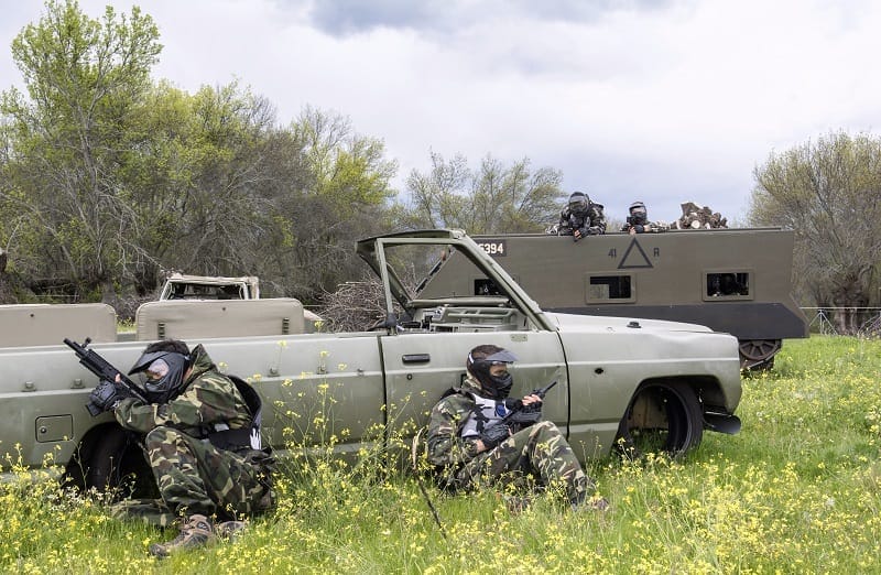 Dors clientes se esconden del enemigo que está en un tanque parapetándose detrás de un vehículo militar