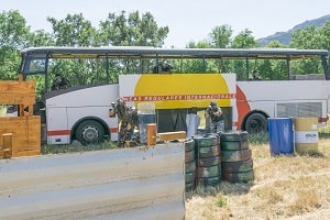 Equipo de piantball avanza desde el autobús con un escudo disparando